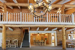 Exterior space featuring log walls, stairs, a wooden ceiling with exposed beams, a high ceiling, and carpet flooring