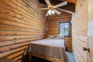 Carpeted bedroom with log walls, a sauna, ceiling fan, wood ceiling, and vaulted ceiling
