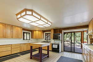Kitchen with light countertops, electric range, and light tile patterned flooring