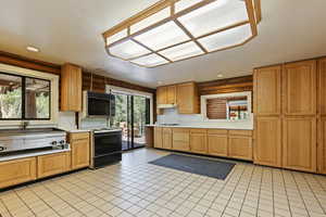 Kitchen with light countertops, plenty of natural light, black electric range, light tile patterned floors, and recessed lighting