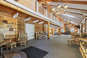 Miscellaneous room featuring a wood stove, high vaulted ceiling, a wood ceiling with exposed beams, rustic walls, and a chandelier
