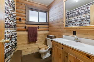 Full bathroom featuring vanity, a textured ceiling, rustic walls, wooden walls, and a shower with shower curtain