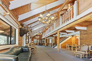 Building lobby featuring rustic walls, a wooden ceiling with exposed beams, stairway, and high vaulted ceiling