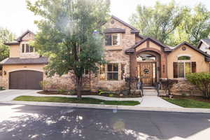 View of front of property featuring stone siding, concrete driveway, stucco siding, and a 2 car garage