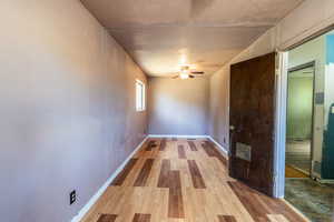 Spare room featuring light wood-style floors, a textured ceiling, and ceiling fan