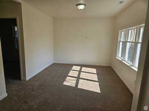 Spare room featuring dark carpet and baseboards
