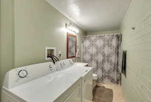Washroom featuring a textured ceiling and separate washer and dryer