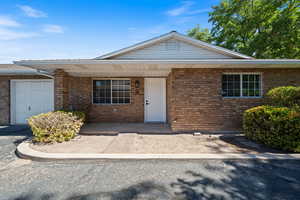 Single story home with a porch, brick siding, and a garage