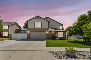 Traditional-style home featuring brick siding, an attached garage, concrete driveway, and a gate