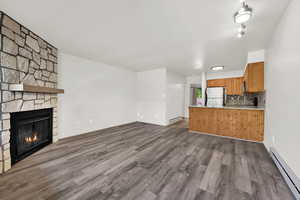 Unfurnished living room featuring a baseboard radiator, dark wood-style floors, a fireplace, and a textured ceiling