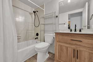Full bath featuring shower / tub combo with curtain, vanity, light wood finished floors, and a textured ceiling