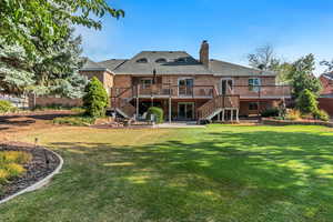 Back of house featuring stairway, a deck, a yard, and brick siding
