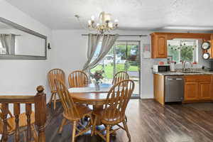 Dining area featuring a chandelier, plenty of natural light, dark wood-style flooring, and a textured ceiling