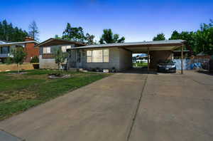 Tri-level home with brick siding, concrete driveway, and a carport
