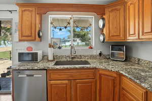 Kitchen featuring brown cabinets, light stone countertops, and dishwasher