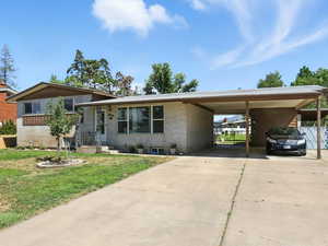 View of front facade featuring brick siding, driveway, and an attached carport