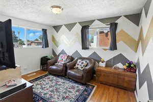 Living room with wood finished floors, a textured ceiling, and an accent wall