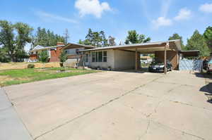 View of front of home featuring a carport, driveway, a front yard, and brick siding