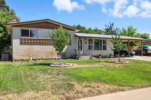 Split level home featuring brick siding, a front yard, and a carport