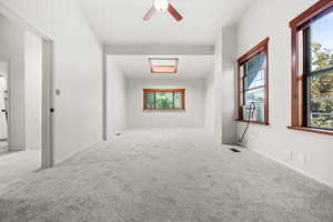Primary bedroom featuring new carpet floors, ceiling fan, and a skylight