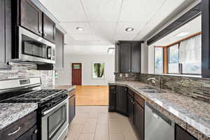 Kitchen with appliances with stainless steel finishes, decorative backsplash, granite countertops, and recessed lighting.