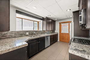 Kitchen featuring dark brown cabinets, granite countertops, appliances with stainless steel finishes, tasteful backsplash, and recessed lighting