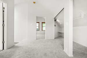 Primary bedroom living space with lofted ceiling and lnew ight carpet
