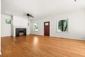 Living room featuring light wood-style floors, healthy amount of natural light, and a tiled fireplace