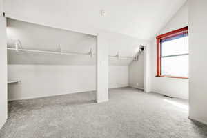 Primary bedroom living space featuring vaulted ceiling and new carpet flooring