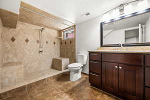 Bathroom featuring vanity, a tile shower, and dark tile patterned floors