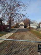 Fenced front yard featuring dirt driveway, a garage, and a deck