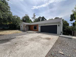 Single story home featuring a garage, roof with shingles, concrete driveway, and a chimney