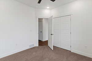 Unfurnished bedroom featuring a closet, carpet, and ceiling fan