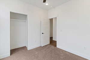 Unfurnished bedroom with a closet, a ceiling fan, and carpet flooring