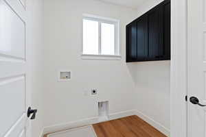 Laundry room with hookup for a washing machine, electric dryer hookup, light wood-type flooring, and cabinet space
