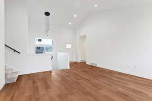 Unfurnished living room featuring vaulted ceiling, wood finished floors, and recessed lighting