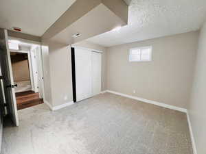 Unfurnished bedroom featuring light carpet, a closet, and a textured ceiling