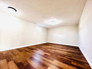 Empty room with a textured ceiling and dark wood finished floors