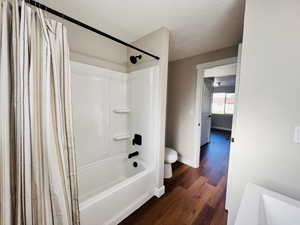 Full bathroom featuring a textured ceiling, dark wood finished floors, and shower / tub combo with curtain