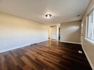 Empty room with dark wood-style flooring and a textured ceiling