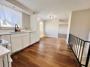 Kitchen with white cabinetry, light wood-style flooring, white appliances, and a textured ceiling