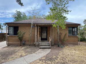 View of front facade featuring brick siding and a shingled roof