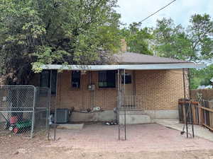 Back of property featuring a porch, brick siding, a chimney, and a patio area