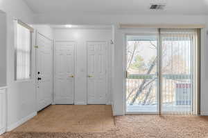 Foyer with light colored carpet and light tile patterned flooring