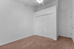 Unfurnished bedroom featuring carpet flooring, a closet, and a ceiling fan