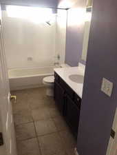 Bathroom featuring vanity, shower / bathtub combination, and dark tile patterned flooring