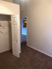 Unfurnished bedroom featuring dark colored carpet and a closet