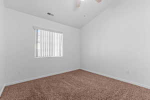 Spare room with vaulted ceiling, ceiling fan, and carpet