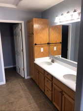 Full bath with double vanity and dark tile patterned floors