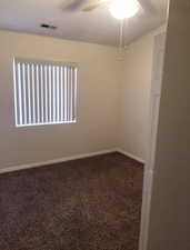 Empty room with dark carpet and ceiling fan